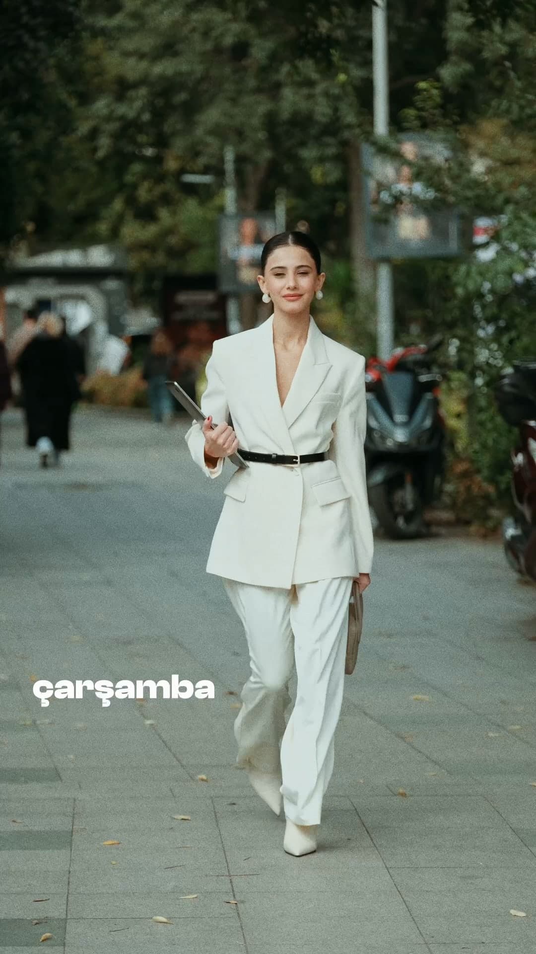 Helin Kandemir walking down an Istanbul street in a cream trouser suit.