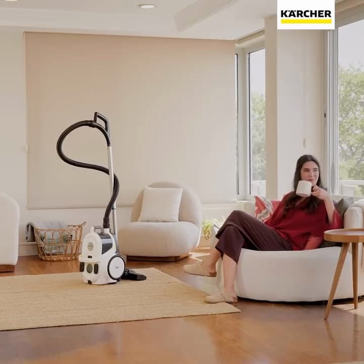 A woman relaxing on a sofa next to a Kärcher vacuum cleaner.